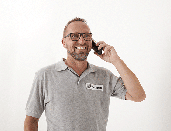 Freundlicher Mitarbeiter mit Brille am Telefonieren.