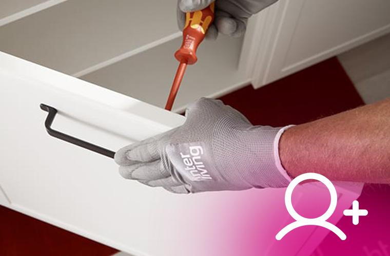 Handwerker montiert schwarzen Griff an weißer Schublade.