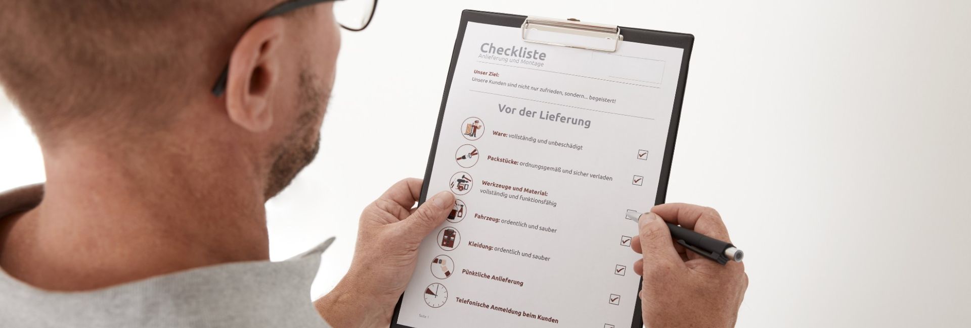 Mitarbeiter des Möbelhauses hält Checkliste in seinen Händen und prüft diese.